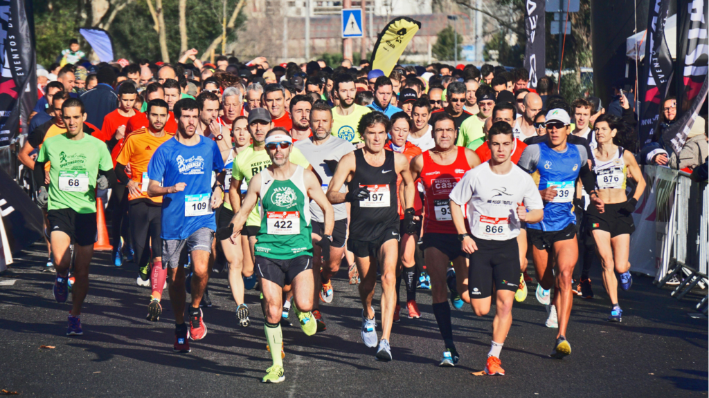 A large group of marathon runners at the starting line, wearing colorful athletic gear and race bibs, competing in a long-distance endurance event.